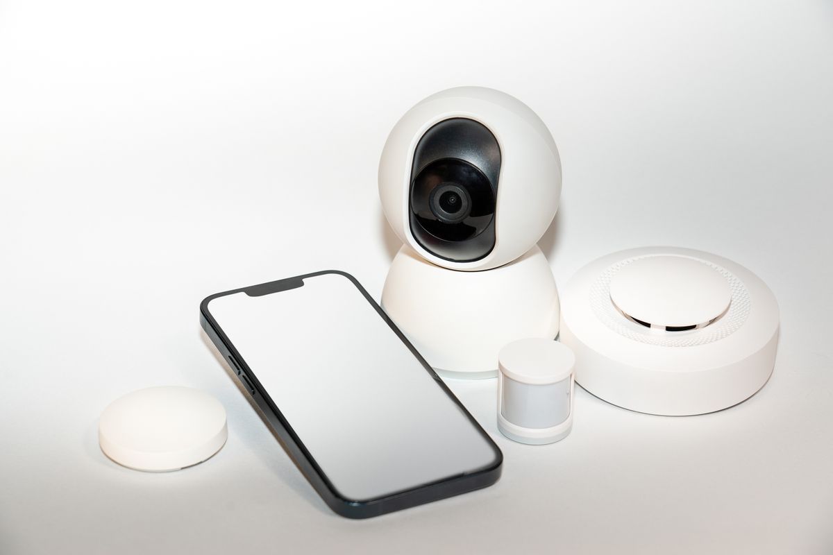 Zestaw urządzeń smart home do ochrony domu obok smartfona