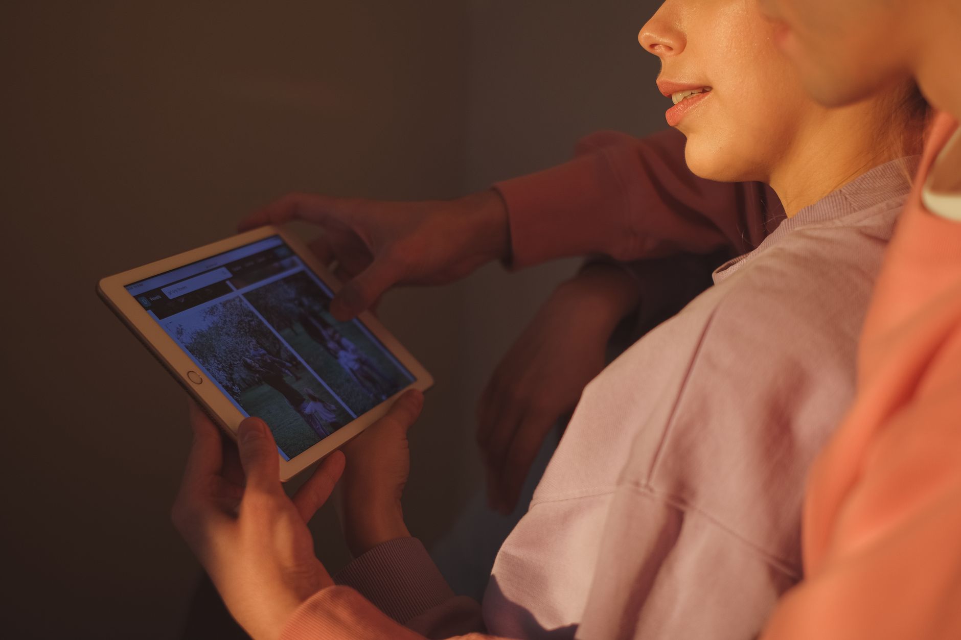 Osoba w bordowym swetrze trzymająca tablet z wyświetlanym interfejsem aplikacji
