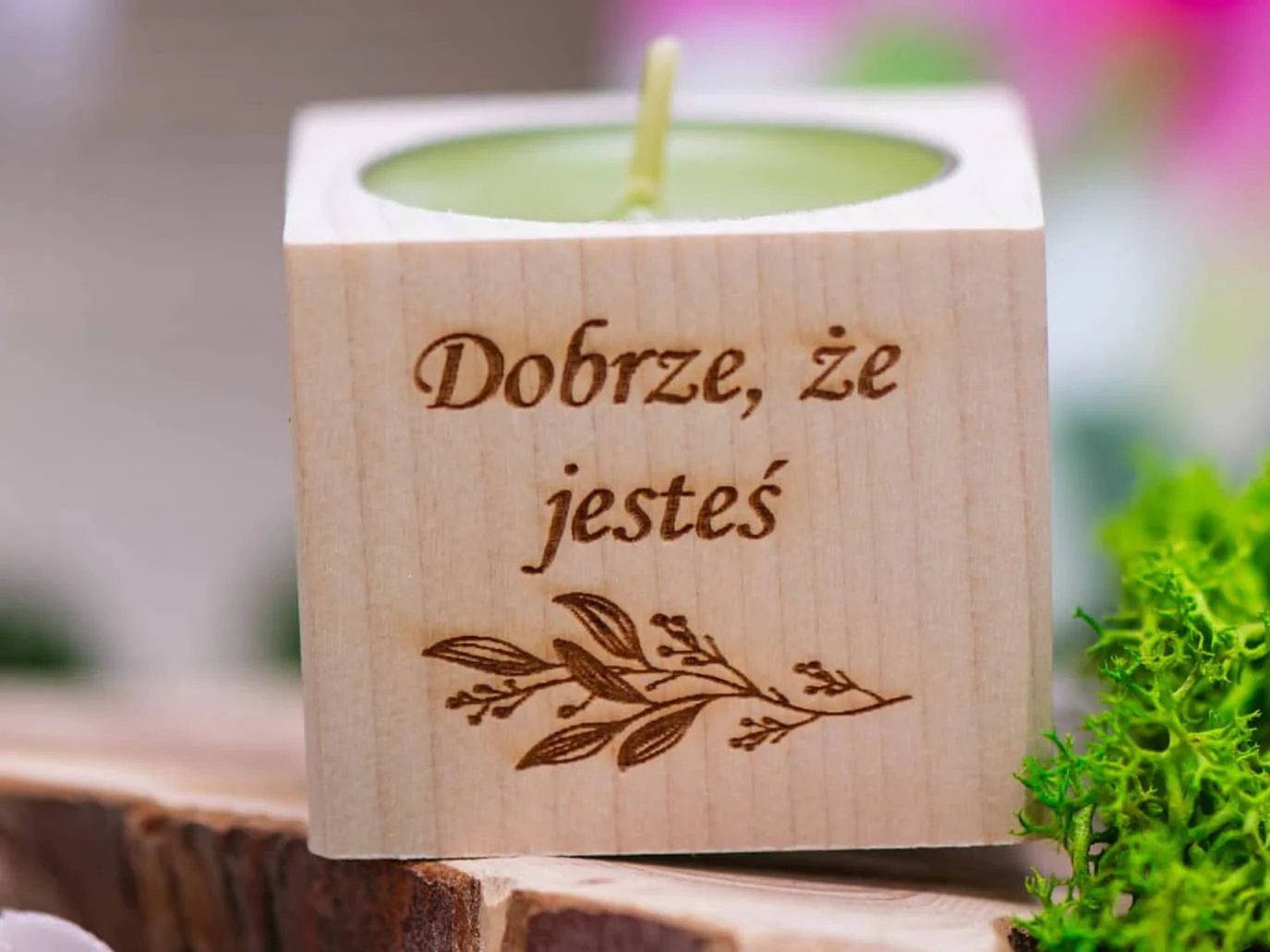 Drewniana świeczka z wyrytym napisem 'Dobrze, że jesteś' i zieloną świecą