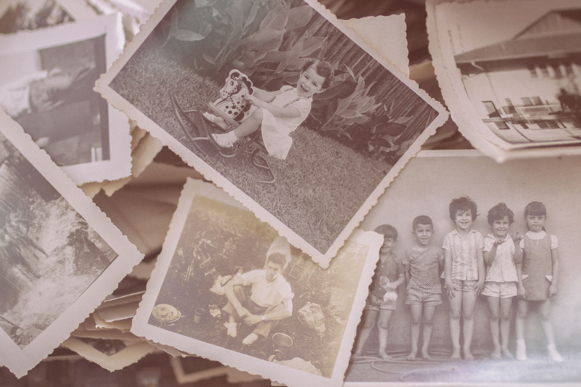Stare czarno-białe zdjęcia rodzinne rozłożone na powierzchni, pokazujące dzieci i dorosłych z różnych epok
